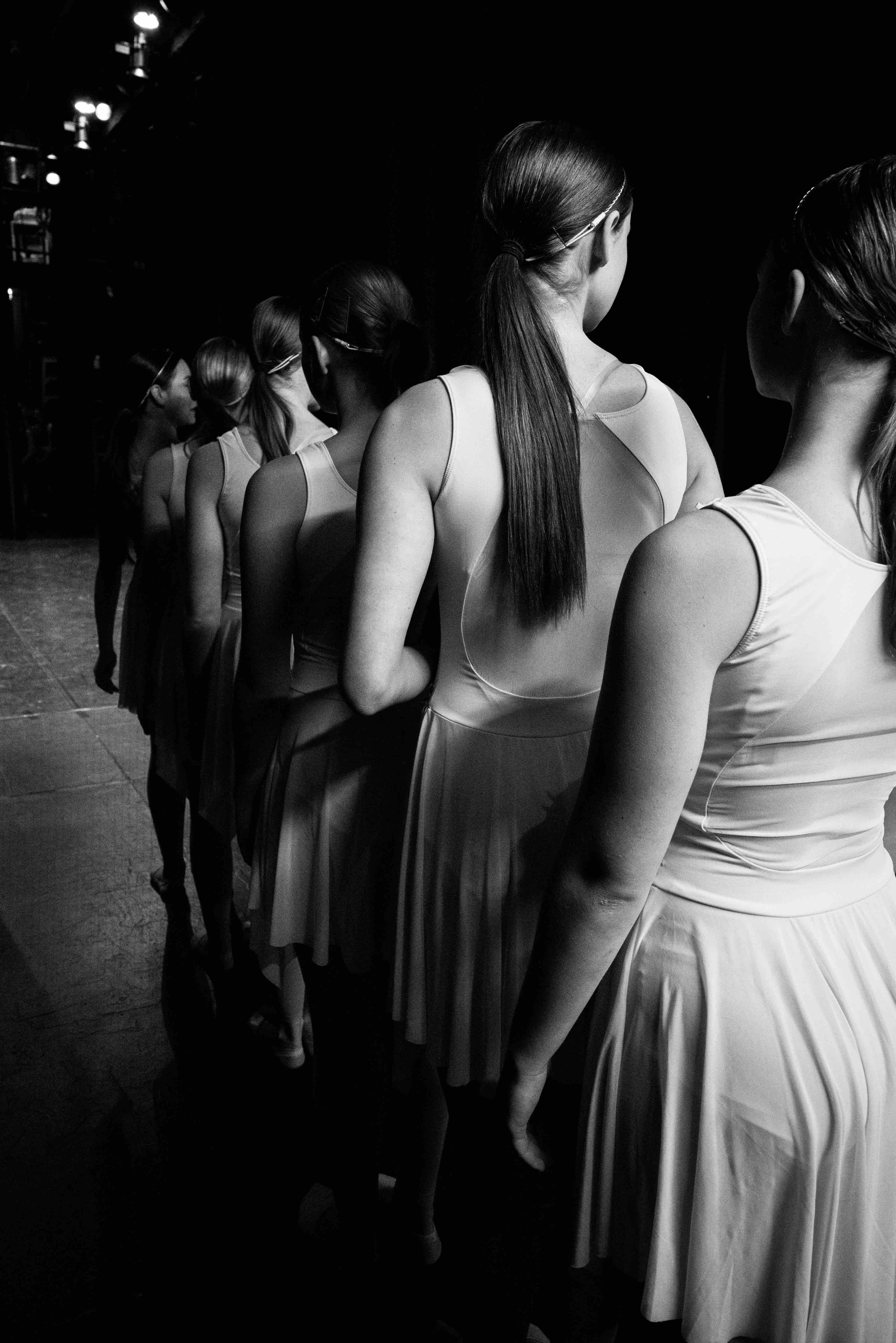 A black and white photo of dancers backstage waiting in the wings.
